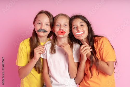 Happy Children hold fake mustache and lips on a pink background. World mental health day.