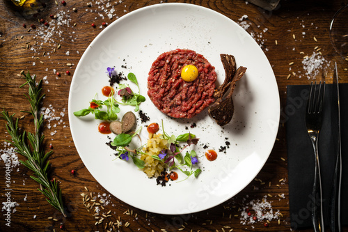 Steak tartare. Horseradish creme  black bread  baguette chips on white plate. Delicious healthy raw meat food closeup served on a table for lunch in modern cuisine gourmet restaurant.