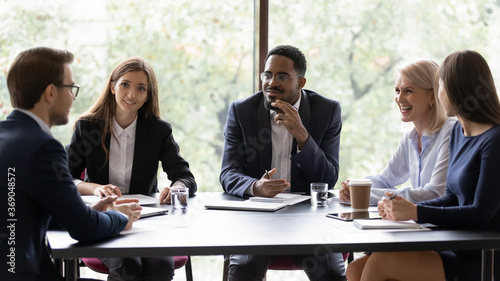 Diverse workmates participating in briefing listen project leader, ceo talking at group meeting in office boardroom. Corporate workshop, effective negotiations, friendly partners communication concept © fizkes