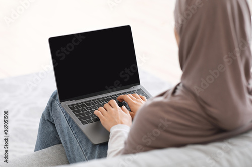 Mockup image of unrecognizable muslim woman working on laptop at home