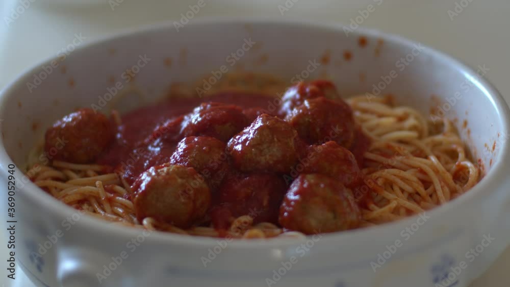 Cooking the spaghetti with red tomato sauce with tasty meatballs on a plate in backlit. Italian food and meal. Slow-motion on stew sauce. Cooking the spaghetti with red tomato sauce with tasty meatballs on a plate in backlit. Italian food and meal. Slow-motion on stew sauce.