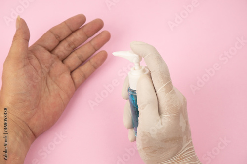 Hand of lady that applying alcohol spray or anti-bacteria spray to prevent the spread of germs  bacteria and virus. Personal hygiene concept.   Isolated on pink background