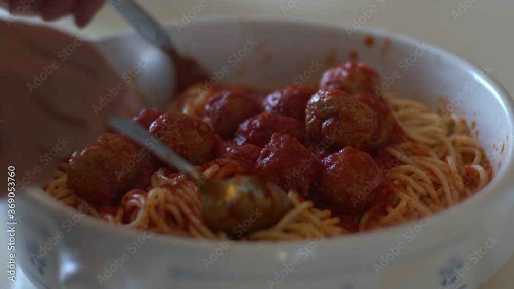 Cooking and stirring the spaghetti with red tomato sauce with tasty meatballs on a plate in backlit. Italian food and meal. Slow-motion on stew sauce. Cooking and stirring the spaghetti with red tomato sauce with tasty meatballs on a plate in backlit. Italian food and meal. Slow-motion on stew sauce.