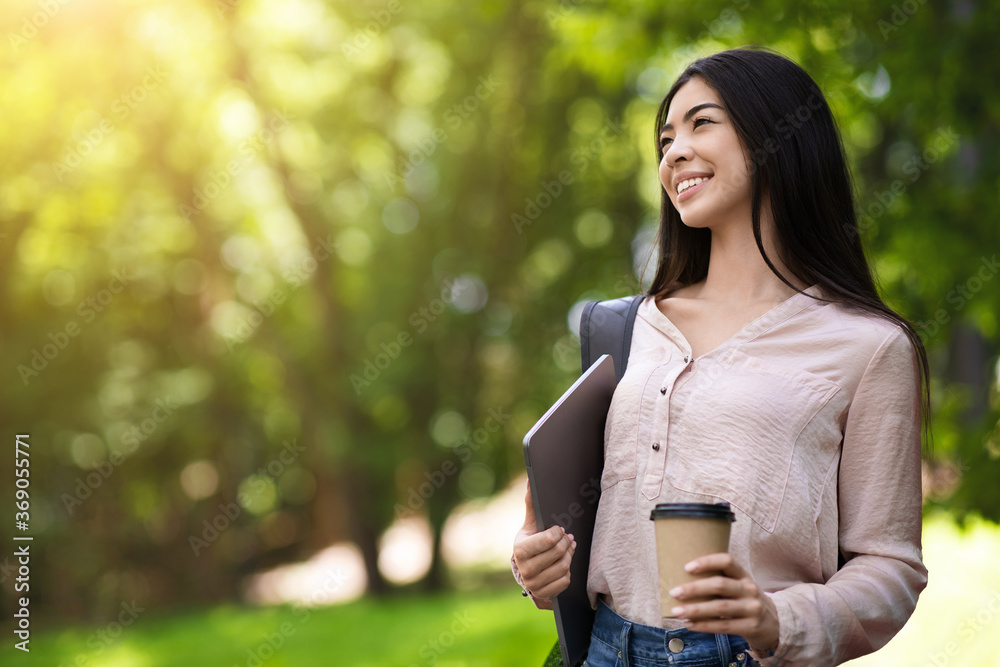 Dreamy Asian Girl Walking In Park With Laptop And Coffee In Hands Dreamy Asian Girl Walking In Park With Laptop And Coffee In Hands