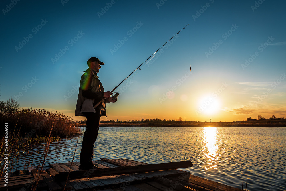 fisherman hold fishing rod at sunset