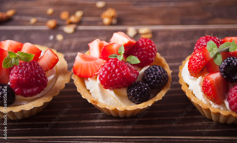 Delicious mini tart tartlets with fresh berries on wooden background