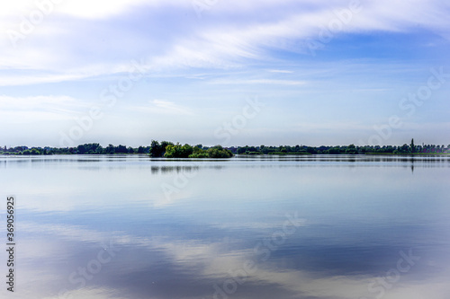 Quiet landscape of a lake in Reeuwijk. The rippling water reflects the fanned out clouds in the sky. South Holland, The Netherlands, Europe. © Karin Reine