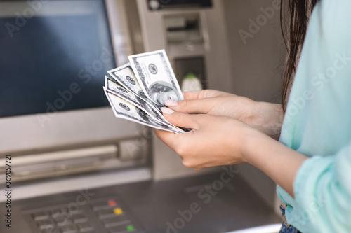 Closeup of female hand counting dollar money cash near street atm