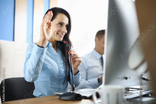 Businesswoman in office holds microphone and greets interlocutor for online communication. Remote learning worldwide concept