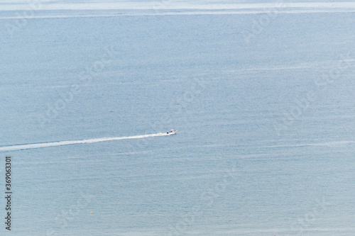 Mediterranean sea with a small recreational boat leaving its trail on the water
