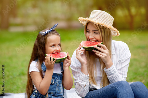 Mother And Daughter Eating Watermelon Sitting On Blanket In Countryside