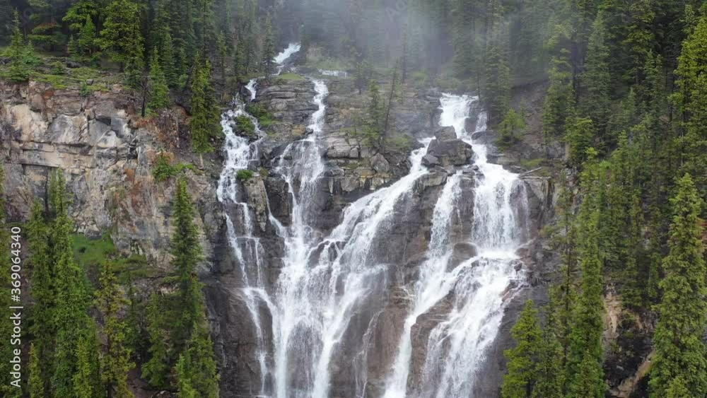 Wide angle view of rushing waterfalls in a steamy forest. Aerial drone shot, slow dolly back. Wide angle view of rushing waterfalls in a steamy forest. Aerial drone shot, slow dolly back.