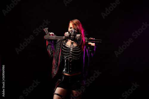 Young woman dressed in a studded leather jacket, gas mask, holding a gun in her hand © Warpedgalerie