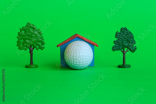 a house by a golf ball surrounded by trees and greenery /a house with a golf ball surrounded by trees and greenery , is the symbol of the presence of a golf -club