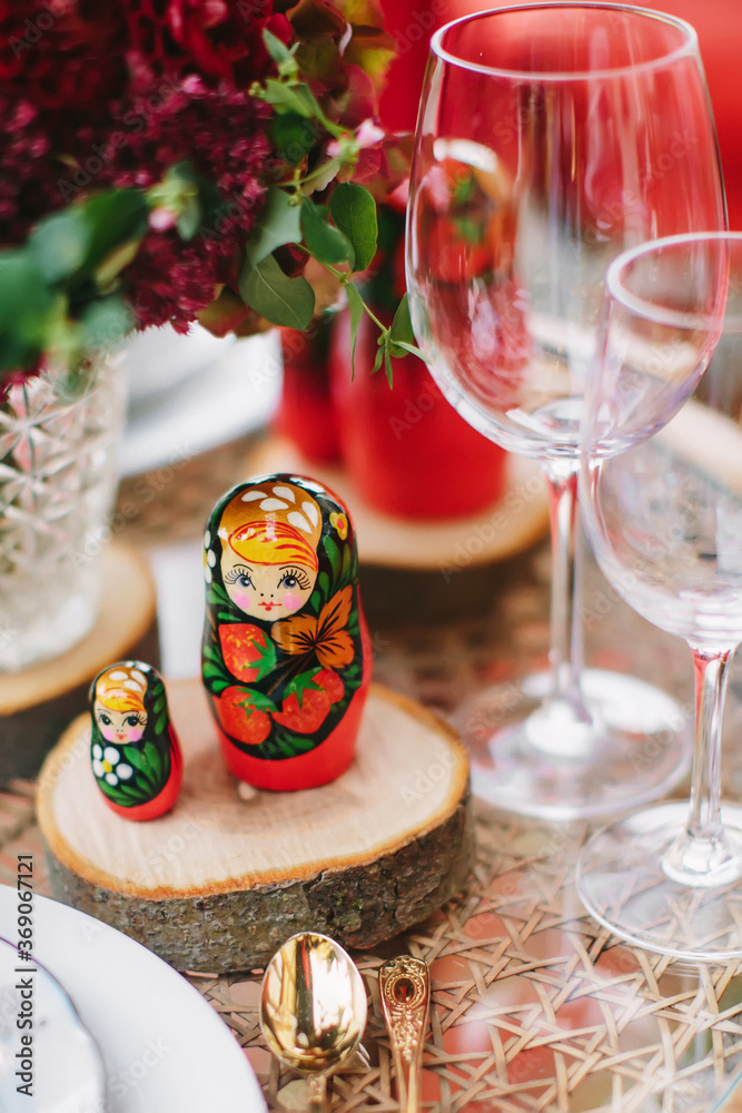 Wooden toy - matryoshka. Table setting in national Russian style. Red in decor and decoration. Wooden toy - matryoshka. Table setting in national Russian style. Red in decor and decoration.