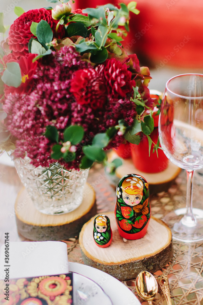 Festive table setting in red, using the national Russian toy - matryoshka. Nesting dolls.