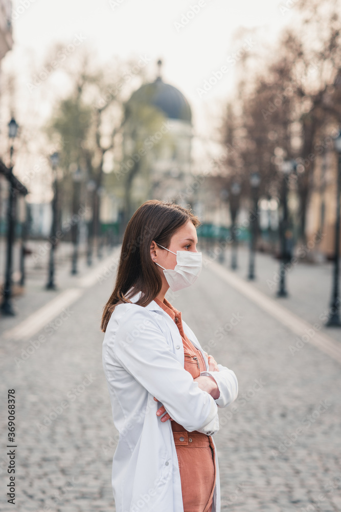 a brunette woman in orange clothes wearing white medical coat and a protective mask on her face a brunette woman in orange clothes wearing white medical coat and a protective mask on her face