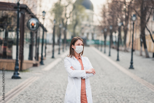 a brunette woman in orange clothes wearing white medical coat and a protective mask on her face