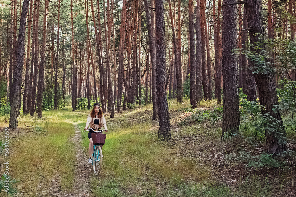 Young woman riding a bike in pine forest Young woman riding a bike in pine forest