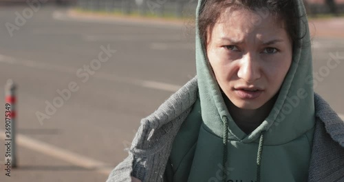 Homeless tramp asian woman in rags on a new York street on a Sunny day talks to the camera
