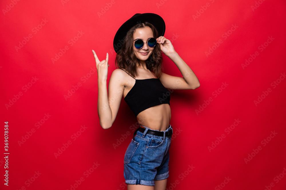 Young beautiful woman shouting with crazy expression doing rock symbol with hands up over isolated red background Young beautiful woman shouting with crazy expression doing rock symbol with hands up over isolated red background