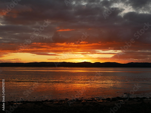 sunset over the hills and water  dramatic grey clouds