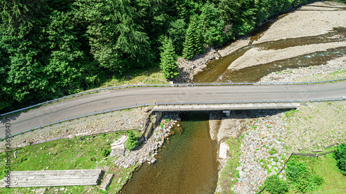 Automobile bridge over the river on the background of the forest in the mountains. Photo from the drone.