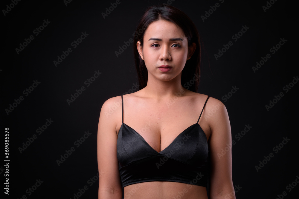 Young beautiful Asian transgender woman against black background