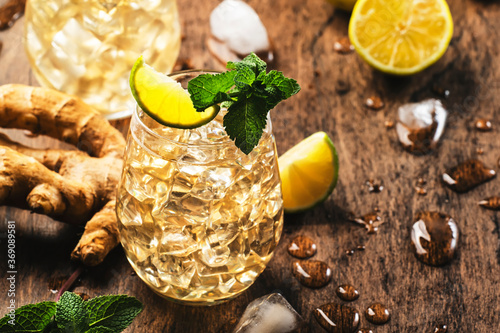 Golden Ginger Ale Beer Cocktail with Lime, Lemon and Mint in glaass on wooden table, copy space photo