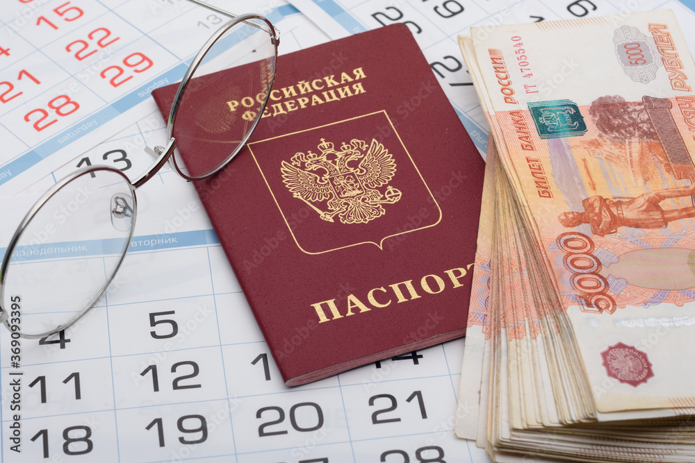 The passport of the Russian Federation lies on the background of calendar numbers, next to it lies a bundle of money and glasses The passport of the Russian Federation lies on the background of calendar numbers, next to it lies a bundle of money and glasses