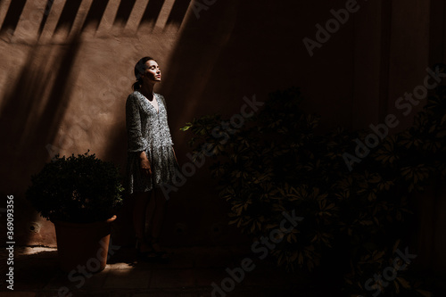 Young female standing by wall in darkness