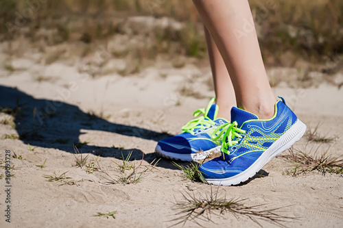 Close up view of a young woman standing on a natural dirt road in sports shoes getting ready to run and exercise