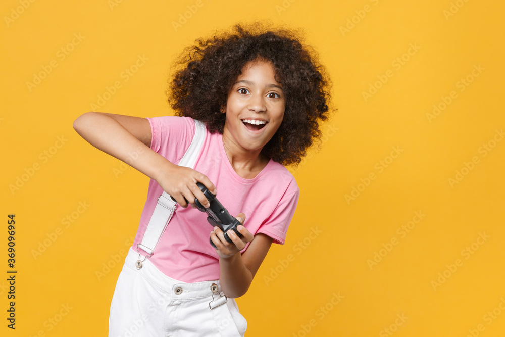 Φωτογραφία Cheerful little african american kid girl 12-13 years old in pink t-shirt isolated on yellow wall background studio portrait
