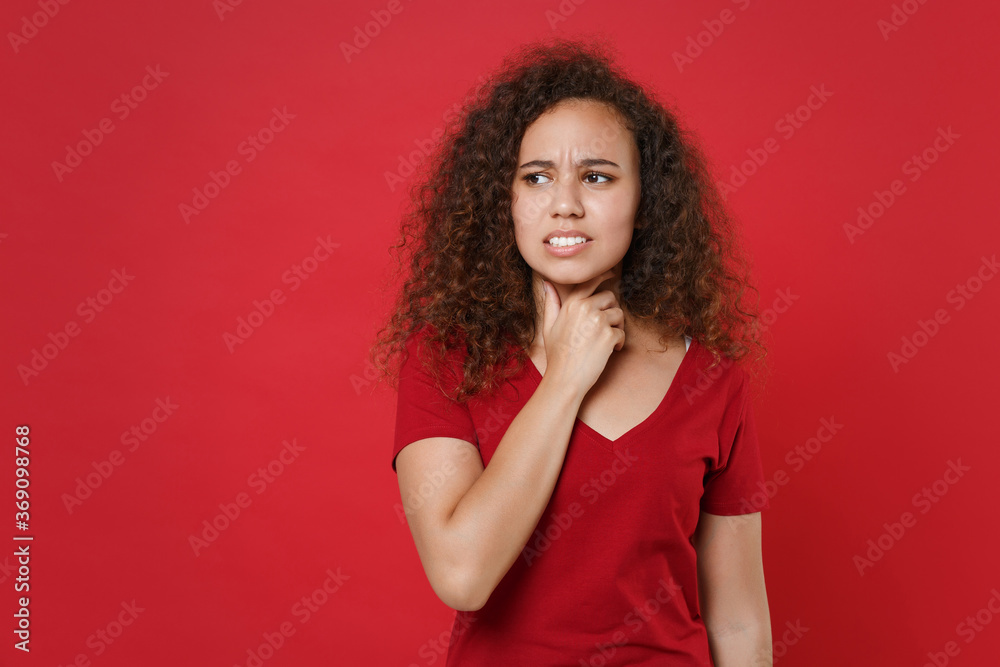 Sick young african american woman girl in casual t-shirt posing isolated on red background studio portrait. People emotions lifestyle concept. Mock up copy space. Having pain, put hand on sore throat. Sick young african american woman girl in casual t-shirt posing isolated on red background studio portrait. People emotions lifestyle concept. Mock up copy space. Having pain, put hand on sore throat.