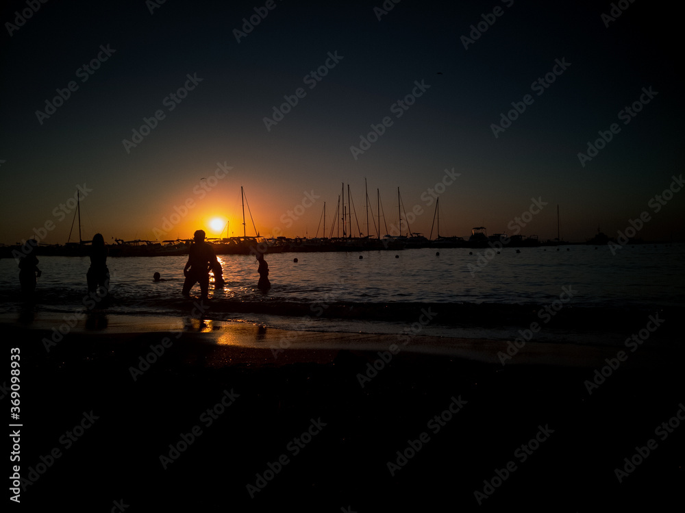 ragazzi giocano nel mare al tramonto