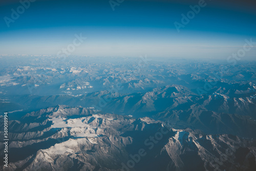 Austria view from airplane, mountains covered by clouds and beautiful landscape from the bird view.