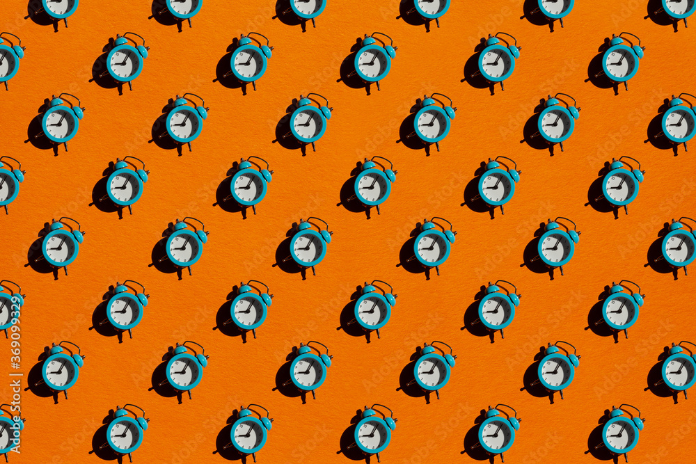 Blue alarm clock on orange background. Pattern. Blue alarm clock on orange background. Pattern.