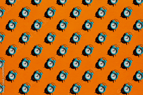 Blue alarm clock on orange background. Pattern. photo