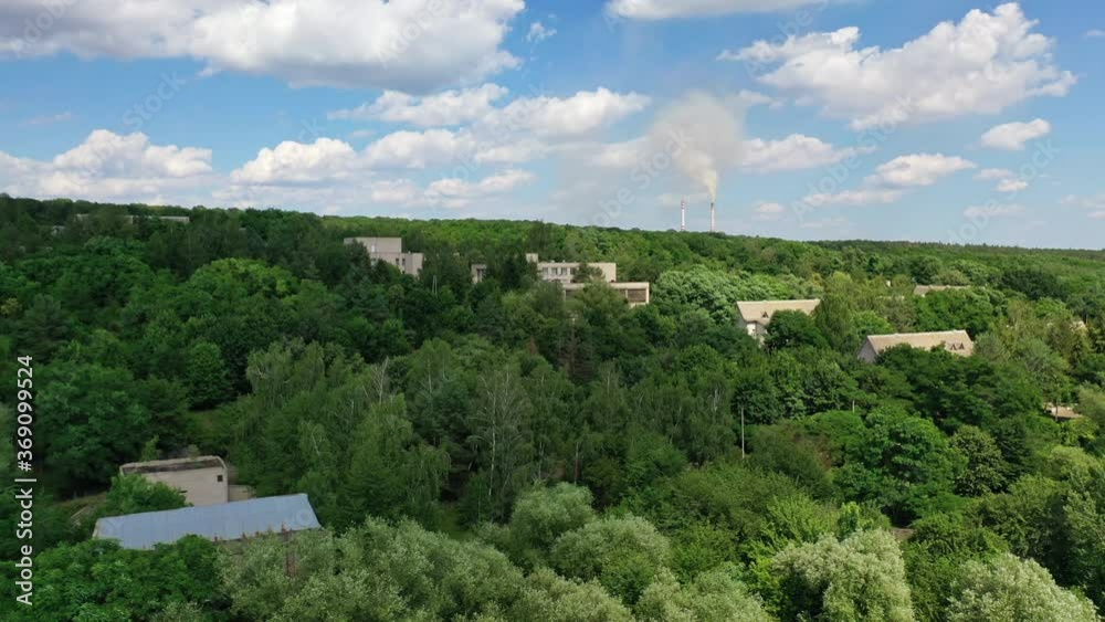Houses in green forest. Roofs of buildings among trees under blue sky. Countryside among beautiful nature. Aerial view. Houses in green forest. Roofs of buildings among trees under blue sky. Countryside among beautiful nature. Aerial view.
