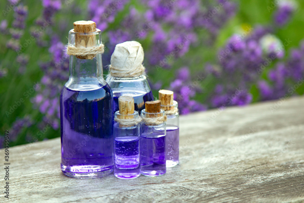 Essential oil bottle and lavender flowers field