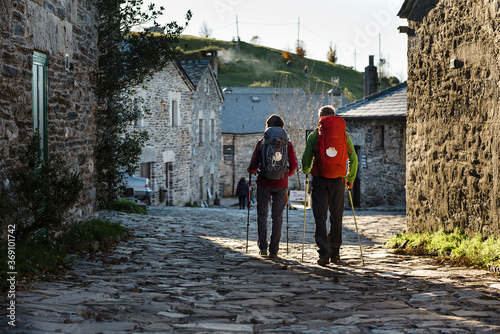 Couple of pilgrims walking along rural village in their way to Santiago de Compostela