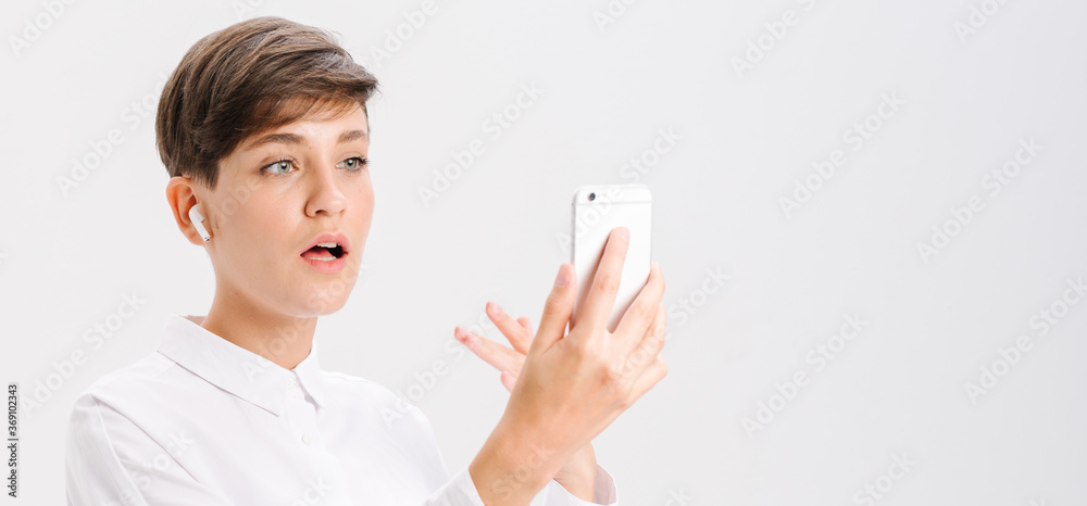 a young girl uses wireless headphones for a video call. white background in studio. online business meeting concept a young girl uses wireless headphones for a video call. white background in studio. online business meeting concept