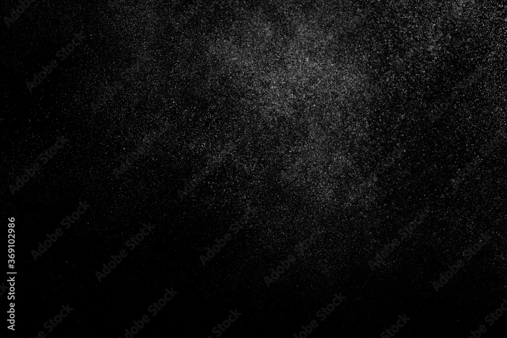 Abstract splashes of water on black background. Freeze motion of white particles. Rain, snow overlay texture.