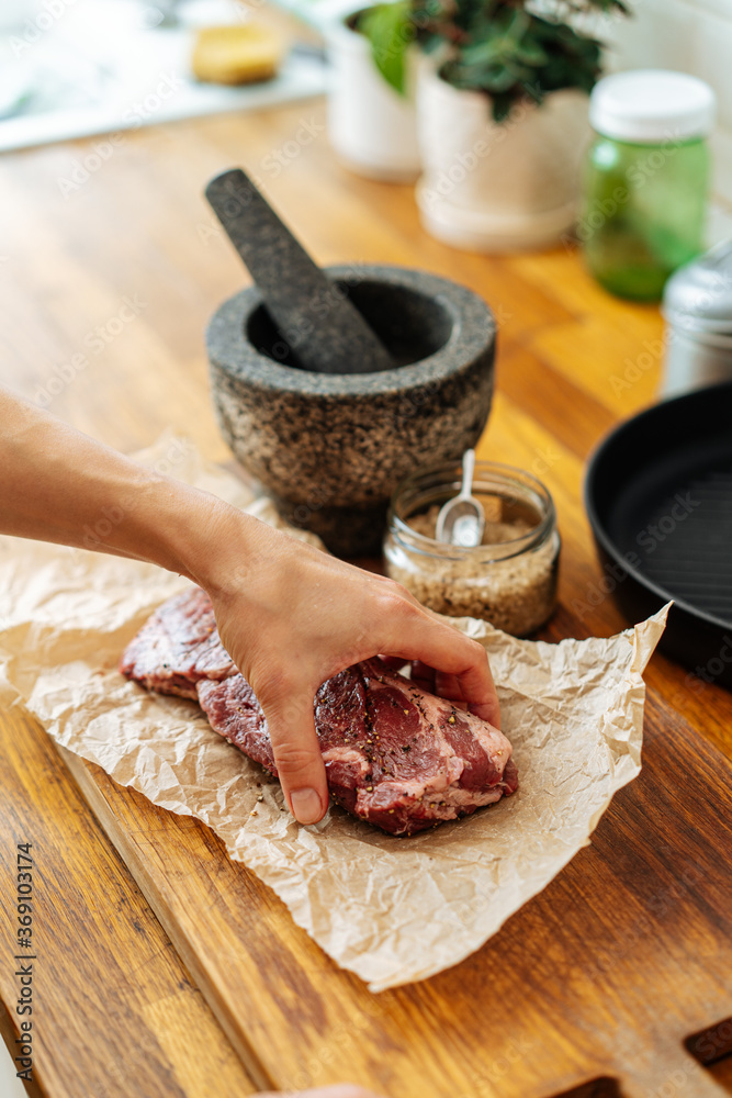Woman placing meat with spices on bakery paper Woman placing meat with spices on bakery paper