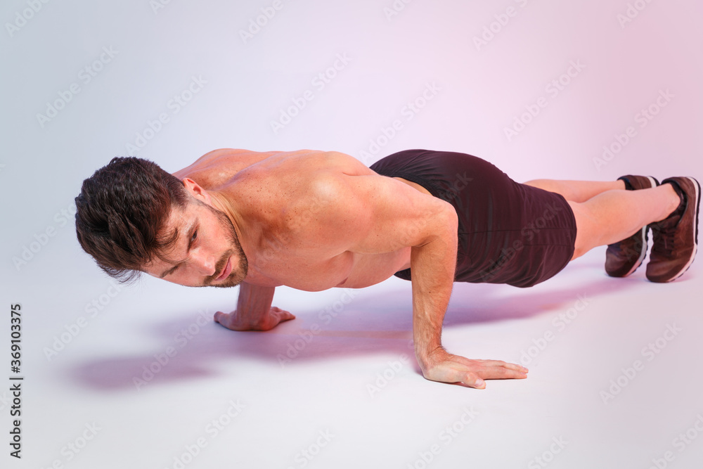 Full length portrait young fitness sporty strong guy bare-chested muscular sportsman isolated on white background. Workout sport motivation lifestyle concept. Doing push-ups exercises, looking aside. Full length portrait young fitness sporty strong guy bare-chested muscular sportsman isolated on white background. Workout sport motivation lifestyle concept. Doing push-ups exercises, looking aside.