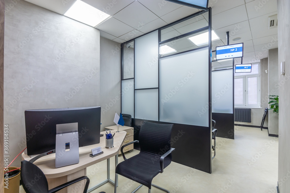 Workplace in the modern sales office with office equipment. Cubicle office with glass panels, office furniture and digital signages Workplace in the modern sales office with office equipment. Cubicle office with glass panels, office furniture and digital signages