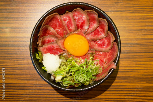 霜降り牛肉のローストビーフ丼、卵黄トッピング。大根おろし。刻みネギ。真上から撮影。一人前。外食、昼ご飯、食堂、オープンキッチン。口コミ、グルメ、行列、人気店。丼物。丼鉢。肉屋。肉々しい。刺身。造り。ユッケ。生物。ナマモノ。レア。薬味。