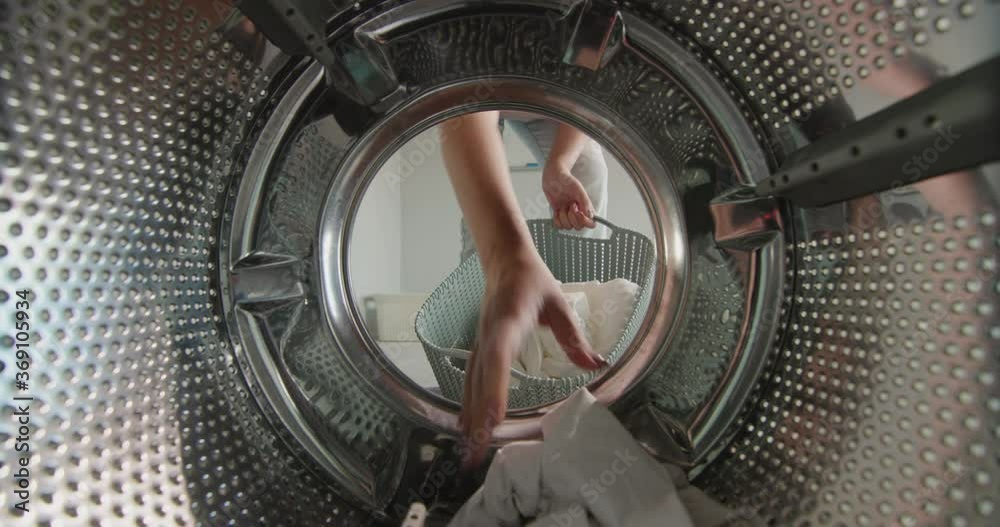 A woman pulls clean washed white linen from the washing machine A woman pulls clean washed white linen from the washing machine