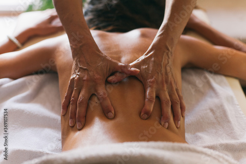 Masseur doing massage of female back indoor photo
