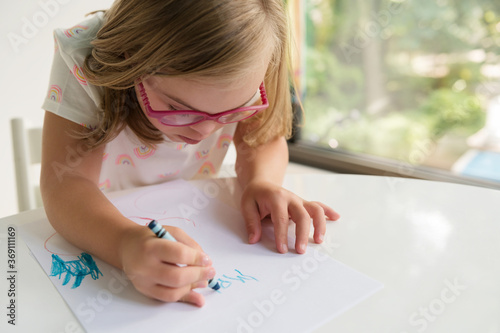 Little girl with down syndrome writing name with crayon photo